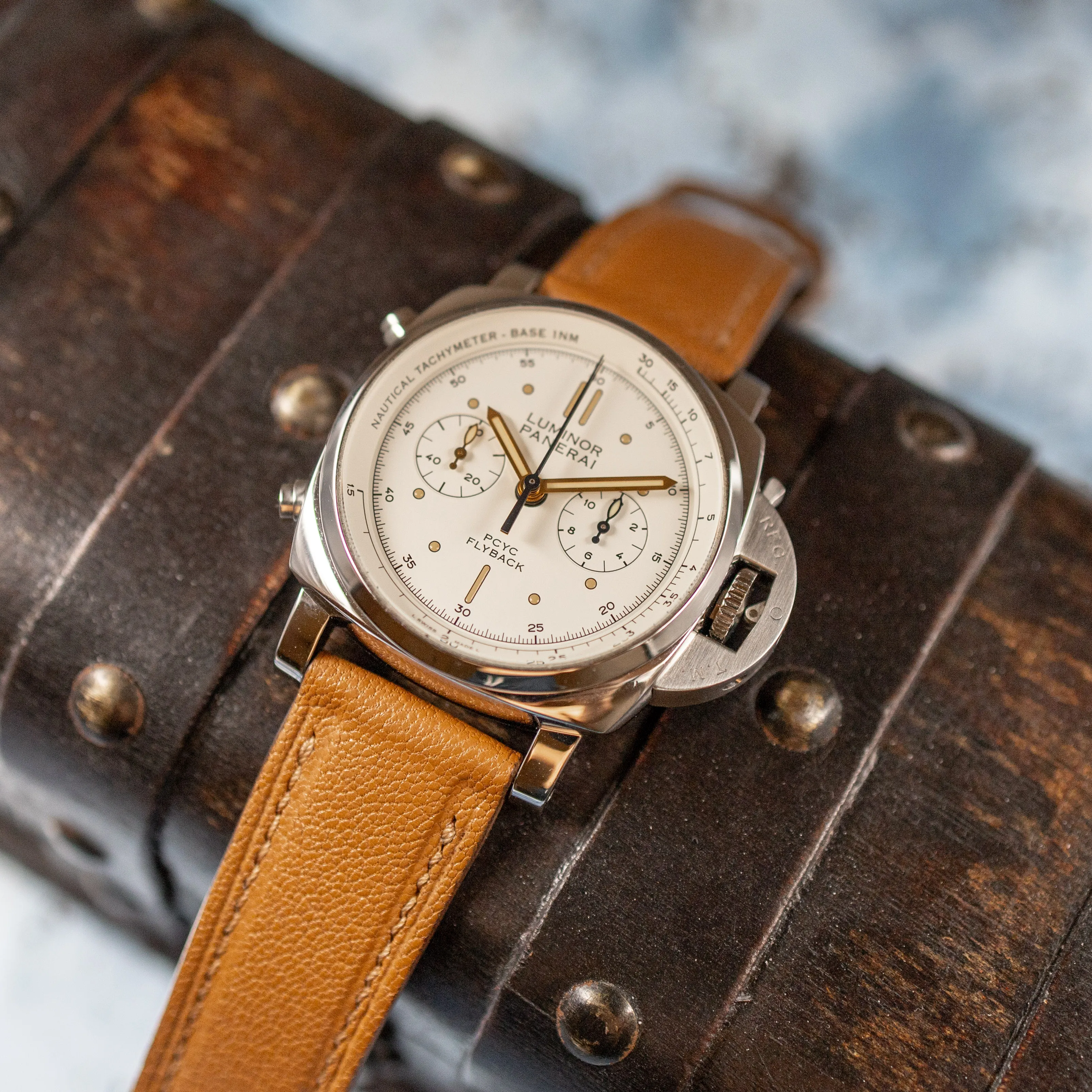 Panerai PAM00654 on brown leather strap resting on a vintage wooden chest